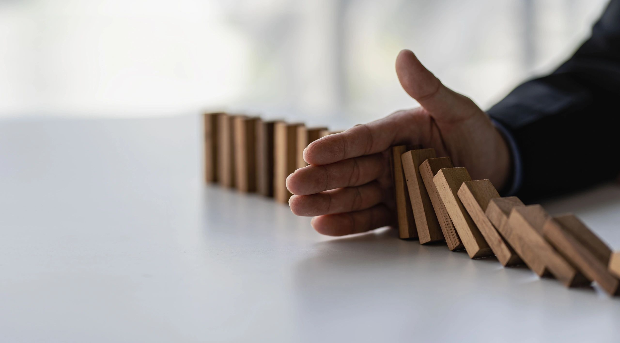 Devrilen ahşap domino taşlarını durduran bir el